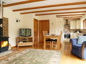 a living room with a table and a fireplace at Cowslip Cottage in Brook