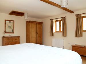 a bedroom with a white bed and two windows at Cowslip Cottage in Brook