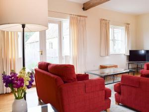 a living room with two red chairs and a table at Len Cottage in Thurning