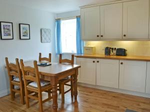 a kitchen with a wooden table and a table and chairs at Havannah Cottage in Alnham