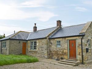 an old stone cottage with a red door at Havannah Cottage in Alnham