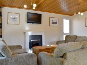 a living room with two couches and a tv on the wall at Lodge E- Uk33091 in Dinnet