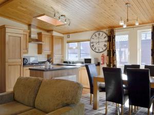 a kitchen with a couch and a clock on the wall at Lodge E- Uk33091 in Dinnet