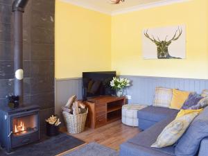 a living room with a blue couch and a wood stove at Thistle Cottage in Mauchline