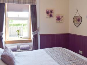 a bedroom with a bed and a window at Thistle Cottage in Mauchline