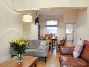 uma sala de estar com um sofá e um vaso de flores sobre uma mesa em Gilberts Warrant em Keswick