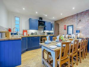 a kitchen with blue cabinets and a table with chairs at Ystwyth House in Borth