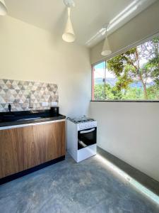 eine Küche mit einem Herd, einem Waschbecken und einem Fenster in der Unterkunft Chalés Vila Do Vale in Vale do Capao