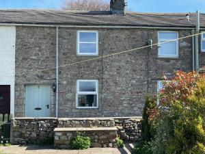 uma casa de pedra com uma parede de pedra em Penny Black Cottage em Ingleton