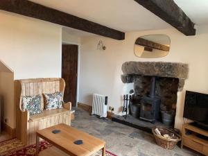 uma sala de estar com uma lareira de pedra e uma mesa em Penny Black Cottage em Ingleton
