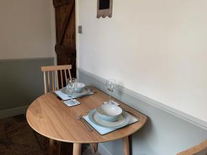 uma pequena mesa de madeira com dois copos e um prato em Penny Black Cottage em Ingleton