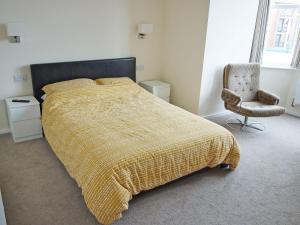 a bedroom with a bed with a yellow blanket and a chair at Deany Apartment in Bridlington