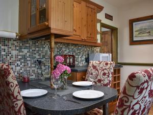 uma cozinha com uma mesa com pratos e flores em Bridge End em Long Preston