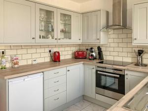 a kitchen with white cabinets and a red appliance at Holmfield in Buxton