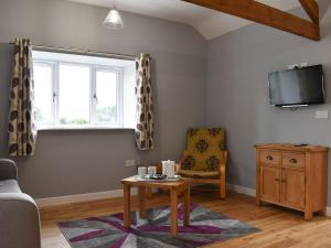 a living room with a table and a chair and a window at Owl Cottage in Ryton