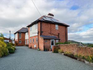 a brick house with a roof on a driveway at Zonnebloem in Cefn-y-bedd