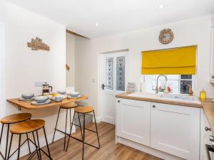 a kitchen with white cabinets and a sink and stools at Court Terrace in Ripon