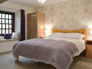a bedroom with a large bed and a window at Smithy House in Bampton