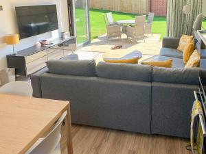 a living room with a blue couch and a table at Hawthorn Cottage in Shirley