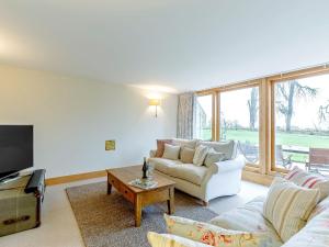 a living room with a couch and a tv at Summerhill Snug in Naunton