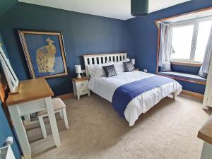 Schlafzimmer mit blauen Wänden, einem Bett und einem Schreibtisch in der Unterkunft Tor Aluinn in Skullomie