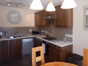 a kitchen with wooden cabinets and a clock on the wall at The Costal Hideaway in Sidmouth