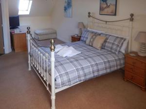 een slaapkamer met een bed met een geruite deken bij The Costal Hideaway in Sidmouth