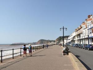 a group of people walking on a sidewalk next to the ocean at The Costal Hideaway in Sidmouth