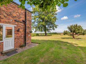 a brick house with a white door and a yard at Edlington Hall Cottage in Edlington