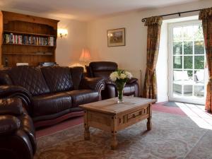 a living room with a leather couch and a coffee table at Hunter House Cottage in Edmondbyers