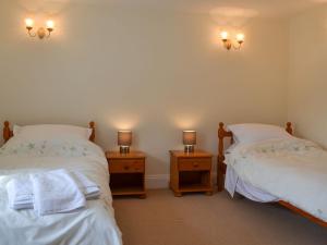 two beds in a room with two lights on the wall at Hunter House Cottage in Edmondbyers
