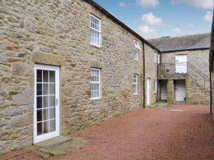 an old stone building with white doors and windows at Hunter House Cottage in Edmondbyers