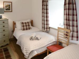 a bedroom with two beds with a dog laying on the bed at Sunset Cottage in Portmahomack