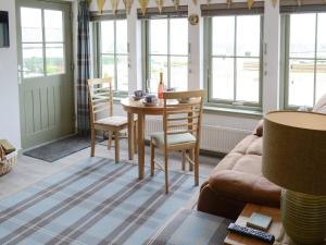 a living room with a table and chairs and windows at Sunset Cottage in Portmahomack