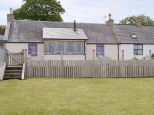 a white house with a wooden fence at Sunset Cottage in Portmahomack