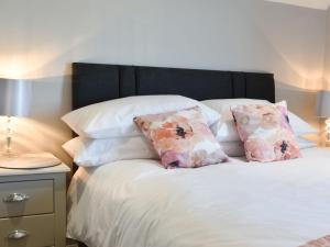 a bed with white pillows and a black headboard at Treacle Cottage - Uk12912 in Warton