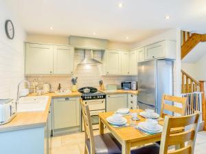 a kitchen with a dining table and a kitchen with a stove and refrigerator at Shepherds Nook - Uk32388 in Dunford Bridge