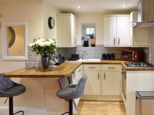 a kitchen with white cabinets and a vase of flowers on a counter at The Mews in Appleby