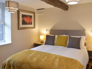 sypialnia z dużym łóżkiem z żółtymi i niebieskimi poduszkami w obiekcie The Mews w mieście Appleby
