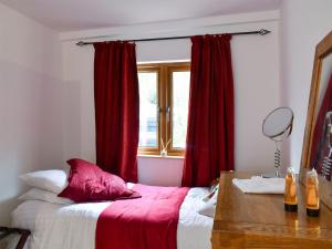a bedroom with a bed with red curtains and a window at Oakwell Lodge in Rainham