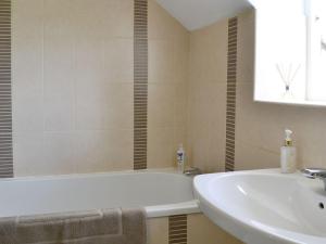 a bathroom with a white tub and a sink at Sandyhouse Cottage in Milfield