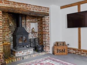a brick fireplace with a stove and a television at Holme Cottage in Eastry
