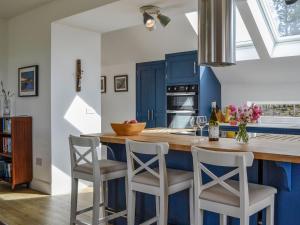 a kitchen with blue cabinets and a counter with stools at Greenford Farm in Newtyle
