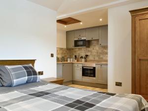 a bedroom with a bed and a kitchen at The Byres Methera in St Bees