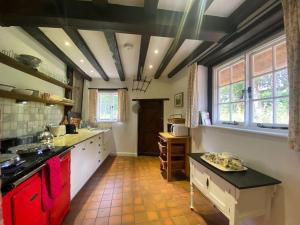 a large kitchen with red cabinets and a large window at Dairy Farm in Sherfield English