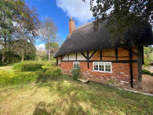 ein altes Backsteinhaus mit einem Strohdach in der Unterkunft Dairy Farm in Sherfield English