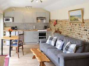 a living room with a couch and a kitchen at Courtyard Barn - Uk11927 in Lessingham