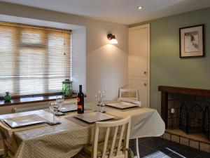 a dining room table with a bottle of wine on it at Cottonmill Cottage in Minnigaff