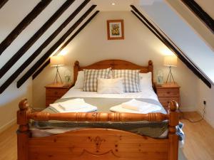 a bedroom with a wooden bed in a attic at Cottonmill Cottage in Minnigaff