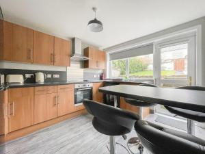 a kitchen with wooden cabinets and a table and chairs at Academy Street Cottage in Tain